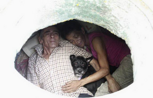Restrepo looks up from his sewer home with his wife Maria Garcia in Medellin
