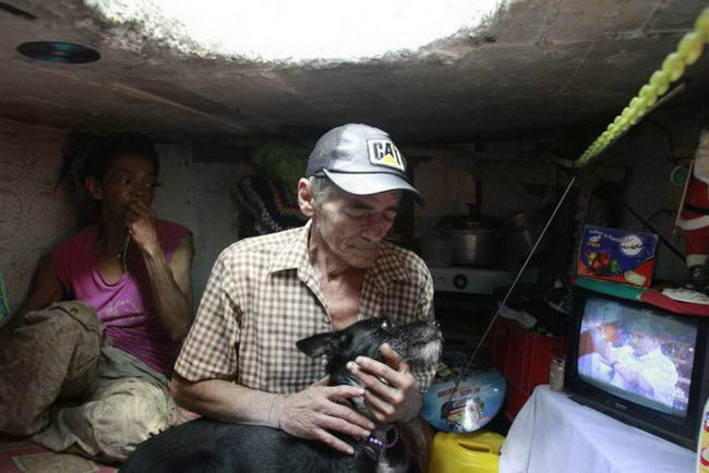 Restrepo plays with his dog Blackie in his sewer home in Medellin